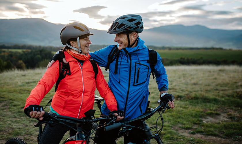 Ein älteres Ehepar in der Natur am Biken im Herbst.